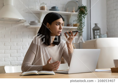 Confident Asian woman recording audio message on smartphone at home 108053407