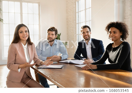 Positive millennial multiethnic startup team sitting at meeting table 108053545