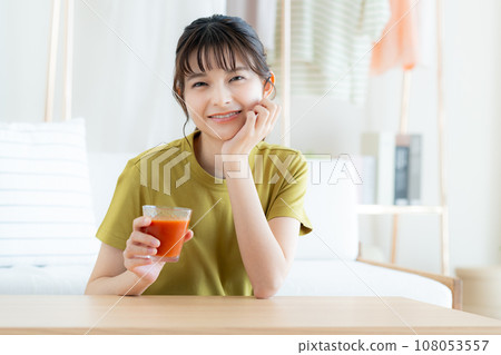 Young woman drinking vegetable juice in the living room Young woman drinking vegetable juice in the living room 108053557