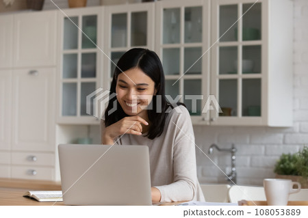 Smiling Asian woman using laptop, studying or working online Smiling Asian woman using laptop, studying or working online 108053889