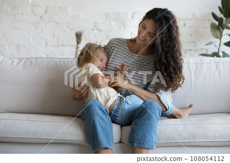 Cheerful happy mom tickling excited daughter kid Cheerful happy mom tickling excited daughter kid 108054112