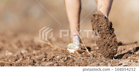 Mud race runners detail of the legs, muddy running shoes a run in the mud Mud race runners detail of the legs, muddy running shoes a run in the mud 108054252