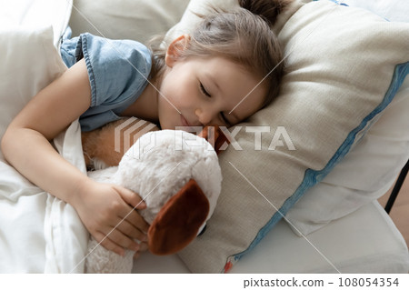 Little preschooler girl sleeping with toy in bed 108054354