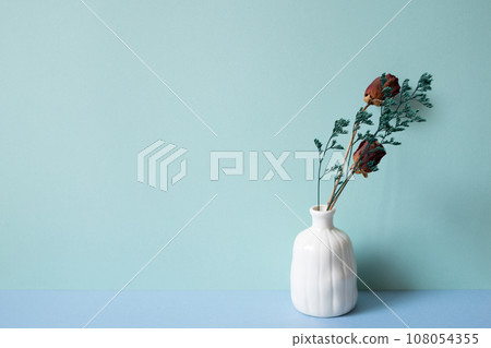 White vase of dry rose flower on blue table. mint green background 108054355