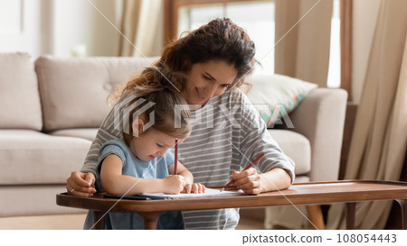 Caring young mom drawing at home with little daughter Caring young mom drawing at home with little daughter 108054443