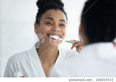 Happy biracial woman brush teeth in bathroom 108054551
