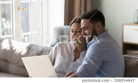 Happy married couple resting on sofa with gadget Happy married couple resting on sofa with gadget 108054647