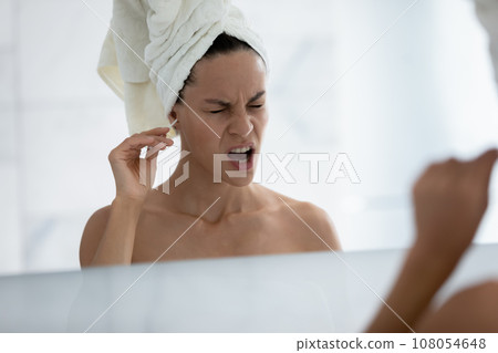 Unhappy young woman feel pain cleansing ears in bath Unhappy young woman feel pain cleansing ears in bath 108054648