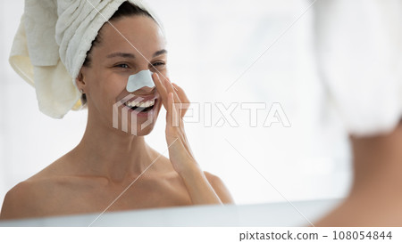 Young woman apply facial nose strips in bathroom 108054844