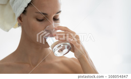 Young woman drink clean water from glass in bathroom Young woman drink clean water from glass in bathroom 108054847