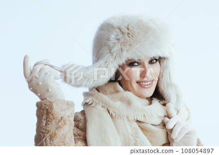 happy stylish woman in winter coat and fur hat on white 108054897