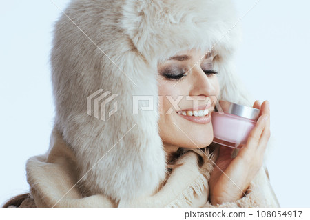 smiling modern woman in winter coat and fur hat on white 108054917