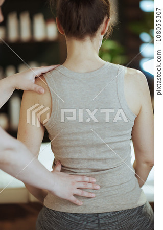 massage therapist checking clients back condition during checkup massage therapist checking clients back condition during checkup 108055307