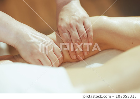 Closeup on medical massage therapist massaging clients arm 108055315