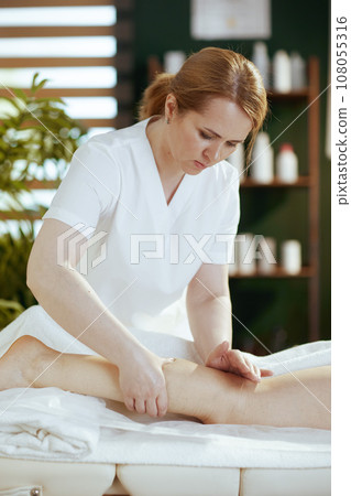 medical massage therapist massaging clients leg 108055316