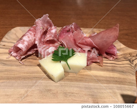 Raw ham and cheese on a stylish cutting board Raw ham and cheese on a stylish cutting board 108055667