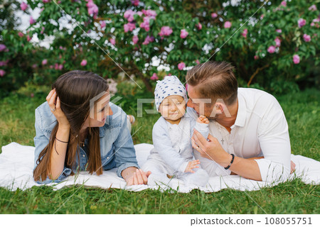 Happy family with young millennial parents and a young son sitting on a picnic blanket and having fun together is a family concept of outdoor lifestyle Happy family with young millennial parents and a young son sitting on a picnic blanket and having fun together is a family concept of outdoor lifestyle 108055751