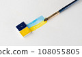 Cuvettes with blue and yellow paint with strips of paint and a brush on a white background place for inscription 108055805