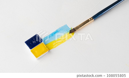 Cuvettes with blue and yellow paint with strips of paint and a brush on a white background place for inscription Cuvettes with blue and yellow paint with strips of paint and a brush on a white background place for inscription 108055805