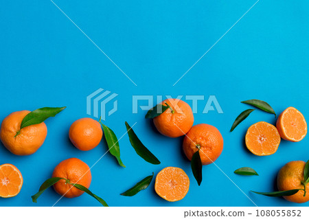 Many fresh ripe mandarin with green leaves on colored background, top view, space for text 108055852