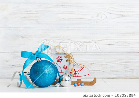 Christmas ball with skates on colored background. decoration bauble with ribbon bow with copy space Christmas ball with skates on colored background. decoration bauble with ribbon bow with copy space 108055894