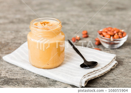 Bowl of peanut butter and peanuts on table background. top view with copy space. Creamy peanut pasta in small bowl Bowl of peanut butter and peanuts on table background. top view with copy space. Creamy peanut pasta in small bowl 108055904
