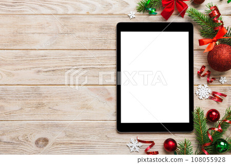 Digital tablet mock up with rustic Christmas decorations for app presentation top view with empty space for you design. Christmas online shopping concept. Tablet with copy space on colored background Digital tablet mock up with rustic Christmas decorations for app presentation top view with empty space for you design. Christmas online shopping concept. Tablet with copy space on colored background 108055928