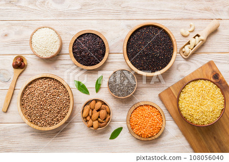 Various superfoods in smal bowl on colored background. Superfood as rice, chia, quinoa, lentils, nuts, sesame seeds, almonds. top view Various superfoods in smal bowl on colored background. Superfood as rice, chia, quinoa, lentils, nuts, sesame seeds, almonds. top view 108056040