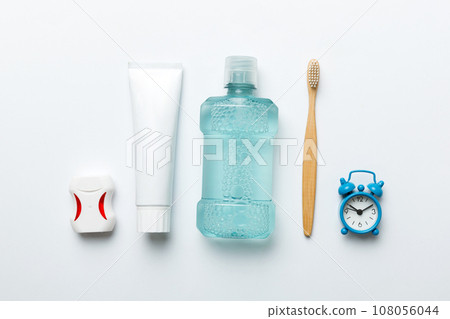 Mouthwash and other oral hygiene products on colored table top view with copy space. Flat lay. Dental hygiene. Oral care products and space for text on light background. concept Mouthwash and other oral hygiene products on colored table top view with copy space. Flat lay. Dental hygiene. Oral care products and space for text on light background. concept 108056044