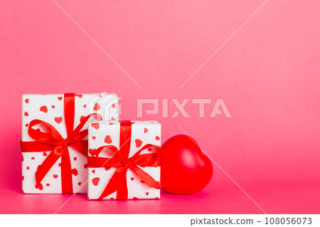 gift box with red bow and red heart on colored background. Perspective view. Flat lay gift box with red bow and red heart on colored background. Perspective view. Flat lay 108056073