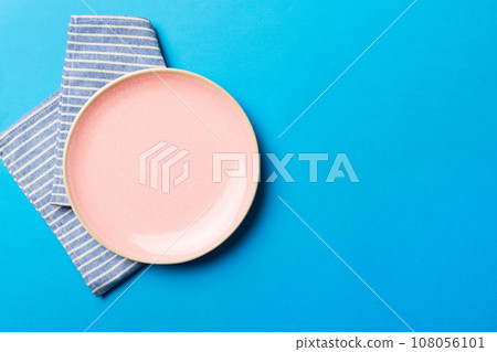 Top view on colored background empty round pink plate on tablecloth for food. Empty dish on napkin with space for your design 108056101