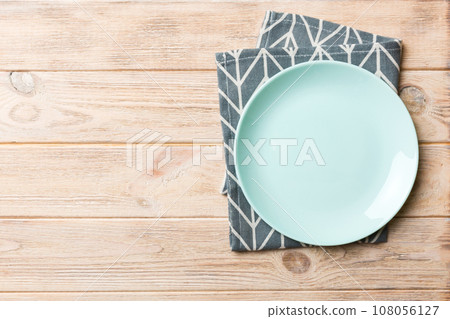 Top view on colored background empty round blue plate on tablecloth for food. Empty dish on napkin with space for your design 108056127