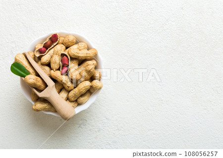 Fresh healthy peanuts in bowl on colored table background. Top view Healthy eating bertholletia concept. Super foods Fresh healthy peanuts in bowl on colored table background. Top view Healthy eating bertholletia concept. Super foods 108056257