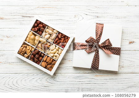 Various varieties of nuts lying in paper box on table background. Top view. Healthy food. Close up, copy space, top view, flat lay. Walnut, pistachios, almonds, hazelnuts and cashews 108056279