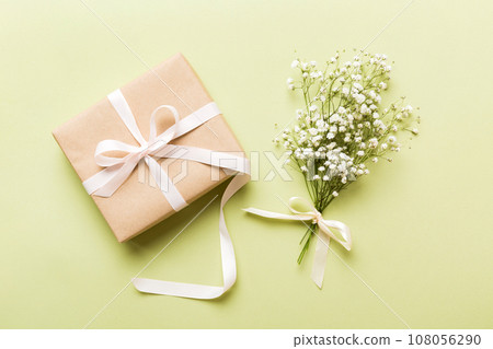 Gift or present box and flower gypsophila on light table top view. Greeting card. Flat lay style with copy space Gift or present box and flower gypsophila on light table top view. Greeting card. Flat lay style with copy space 108056290