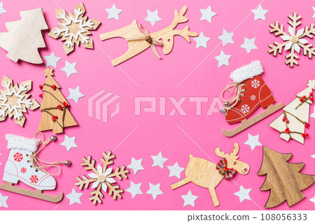 Top view of pink background decorated with festive toys and Christmas symbols reindeers and New Year trees. Holiday concept with copy space 108056333