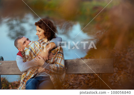 boyfriend and girlfriend embracing while sitting on bench boyfriend and girlfriend embracing while sitting on bench 108056840