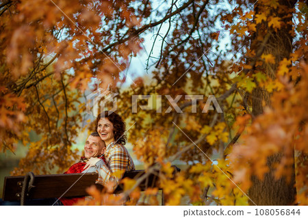 happy stylish couple in park sitting on bench 108056844