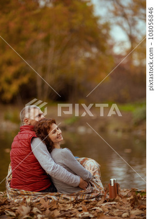 relaxed modern couple in park with thermos hugging 108056846