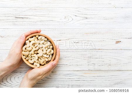 Woman hands holding a wooden bowl with cashew nuts. Healthy food and snack. Vegetarian snacks of different nuts 108056916