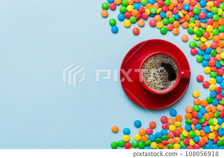 Coffee cup with chocolates and colored candy. Top view on table background with copy space Coffee cup with chocolates and colored candy. Top view on table background with copy space 108056918