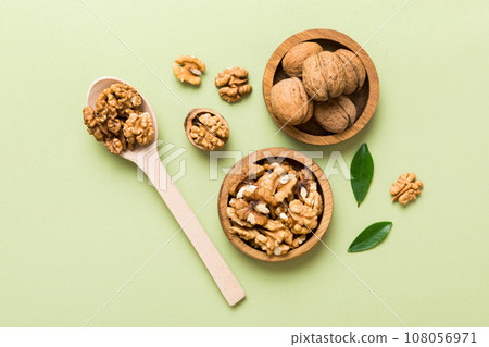 Walnut kernel halves, in a wooden bowl. Close-up, from above on colored background. Healthy eating Walnut concept. Super foods with copy space Walnut kernel halves, in a wooden bowl. Close-up, from above on colored background. Healthy eating Walnut concept. Super foods with copy space 108056971