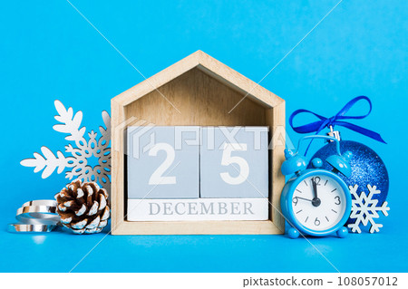 25 december. Christmas composition on colored background with a wooden calendar, with a gift box, toys, bauble copy space 108057012