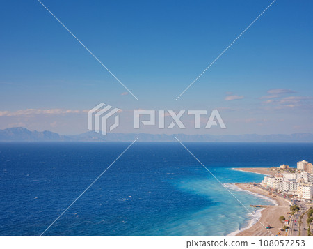 Travel to Greece, Mediterranean islands Rhodes. Aegean beach with sunshades in city of Rhodes view above Travel to Greece, Mediterranean islands Rhodes. Aegean beach with sunshades in city of Rhodes view above 108057253