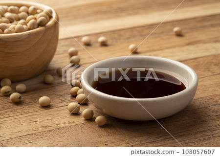 Soy sauce in a bowl and soy bean on wooden table Soy sauce in a bowl and soy bean on wooden table 108057607