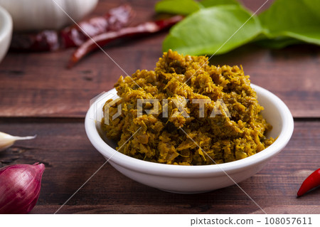 Thai green curry paste in white bowl, made from a mixture of herbs and spices on wood table (prik gaeng keow waan) 108057611