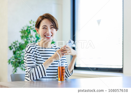 A woman using her smartphone in a cafe A woman using her smartphone in a cafe 108057638
