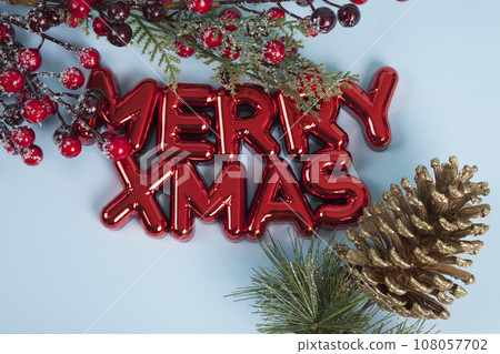gold pine cone and A glossy red plastic Christmas ornament featuring a text saying merry xmas. gold pine cone and A glossy red plastic Christmas ornament featuring a text saying merry xmas. 108057702