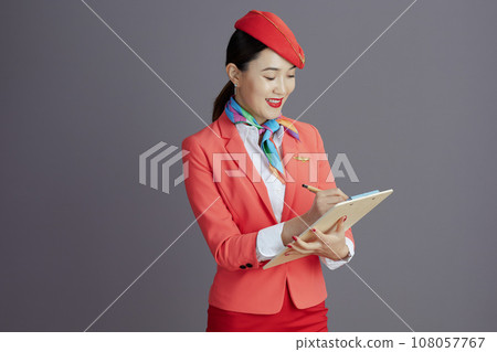 smiling stylish asian female flight attendant isolated on grey 108057767