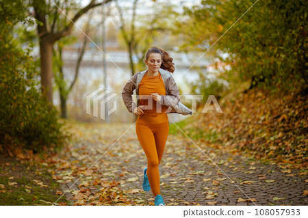 elegant woman in fitness clothes in park running 108057933